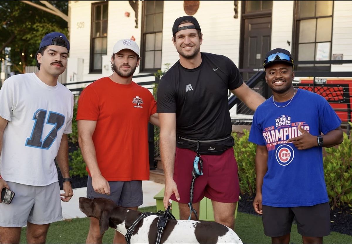 Four runners posing with a dog on the turf before a Sunday run in downtown Woodstock