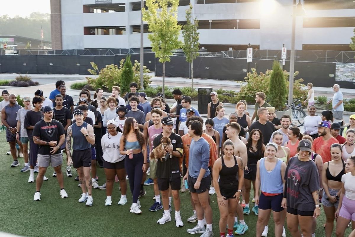 A large group of Flyte Run Club runners gathered on the turf in downtown Woodstock at sunrise